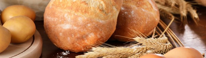 Celiakia - co to za choroba, jak się objawia i co ma wspólnego z dietą bezglutenową? Bułki pszenne, mąka pszenna i jajka na drewnianym stole.