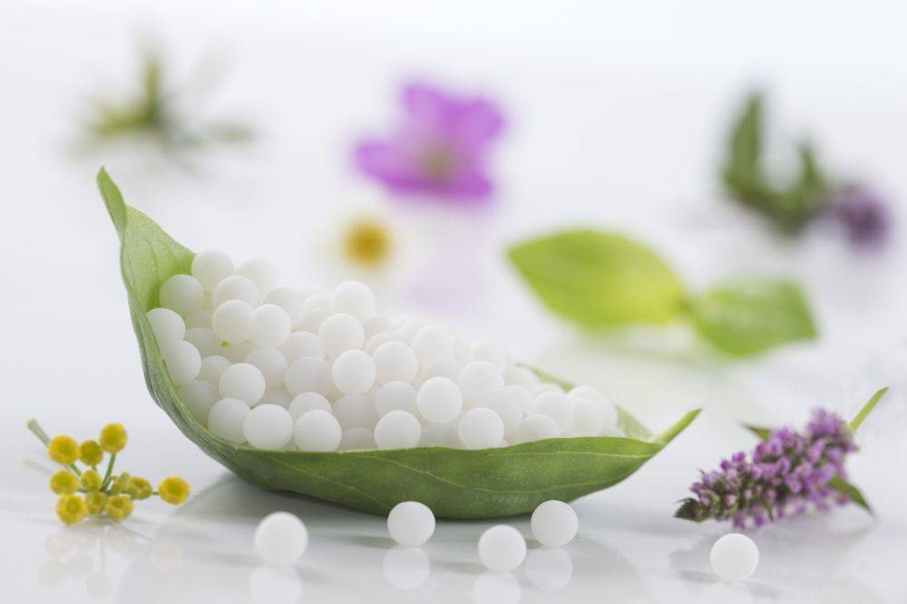 Leki homeopatyczne w granulkach na liściu.