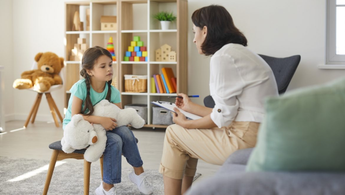 Jak rozmawiać z dzieckiem o wojnie i o zagrożeniu? Mała dziewczynka rozmawia z mamą lub panią psycholog.