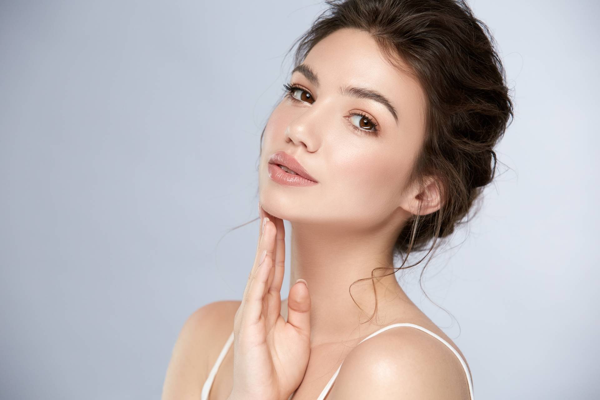Facemodeling - na czym polega manualna terapia twarzy? Zbliżenie na twarz młodej kobiety, której cera jest świeża i pełna blasku.