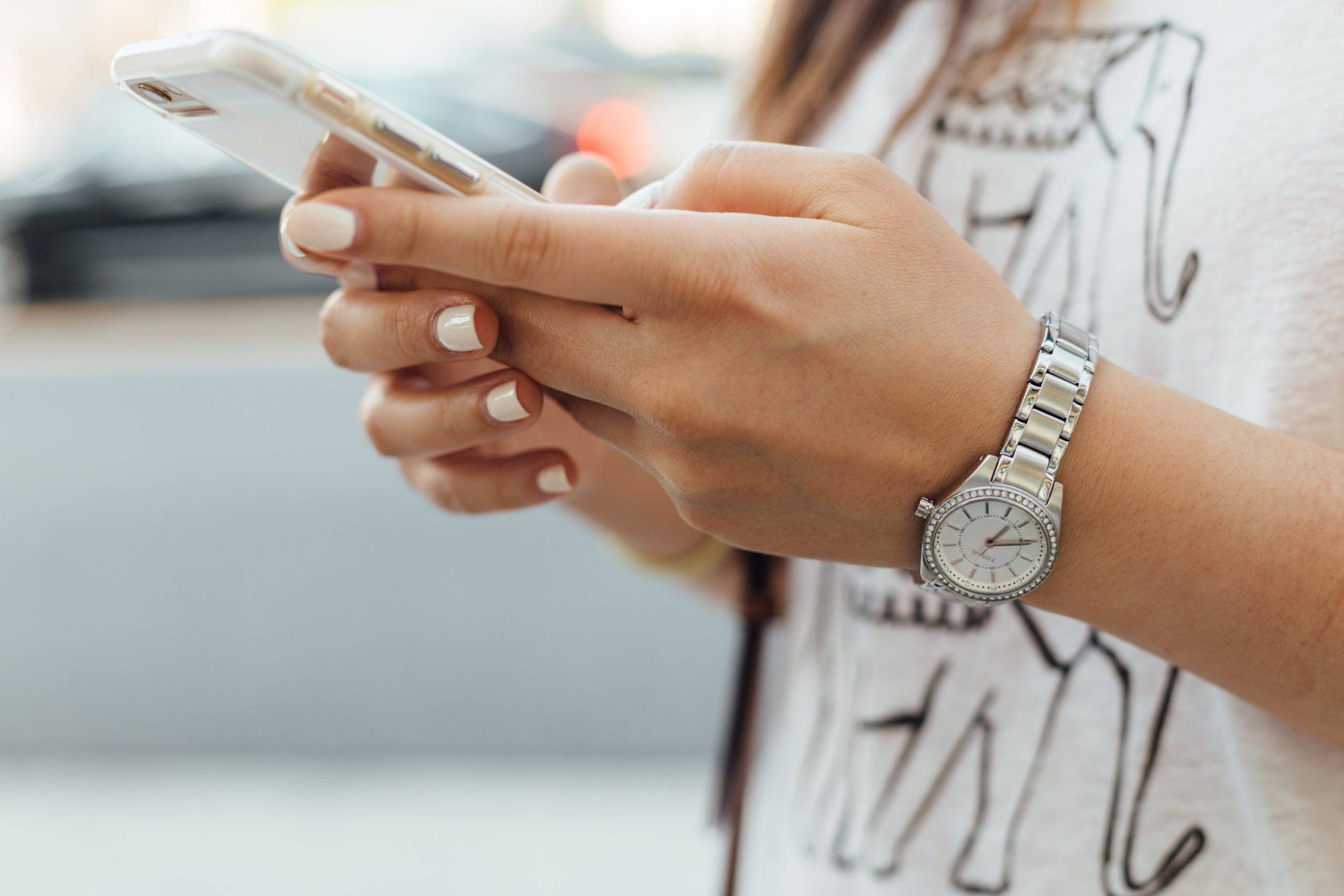 Czym grozi FOMO? Dlaczego uzależniamy się od informacji? Kobiece ręce trzymają smartfon.