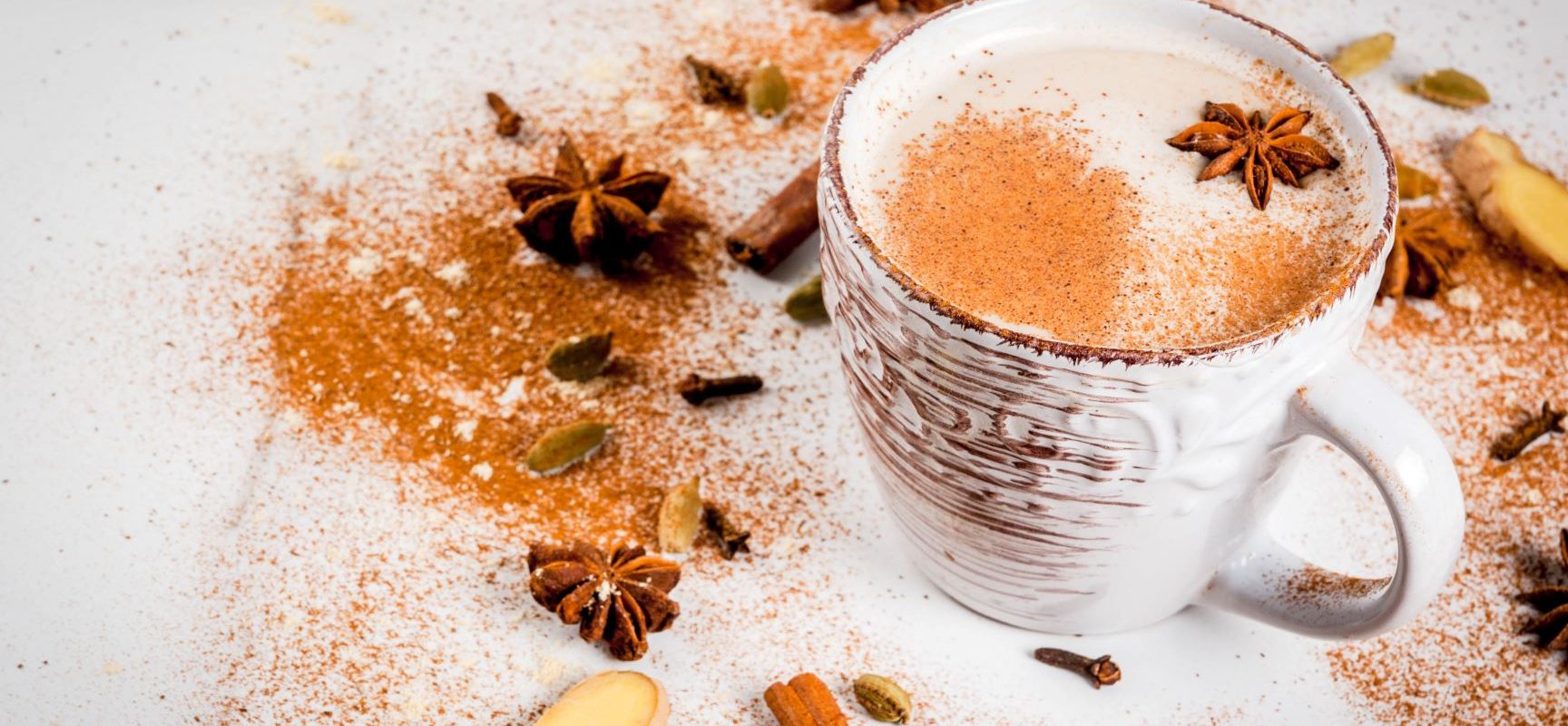 Herbata masala - jakie ma właściwości i jakie jest przepis na indyjską herbatę chai? Herbata masala w kubku z przyprawami w zimowej aranżacji.