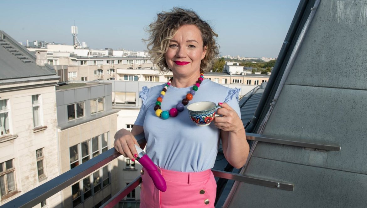 Joanna Keszka, sex coach, opowiada o kobiecej seksualności. Twórczyni portalu Barbarella stoi na tarasie z filiżanką kawy w jednej ręce i wibratorem w drugiej, w tle miejskie kamienice.