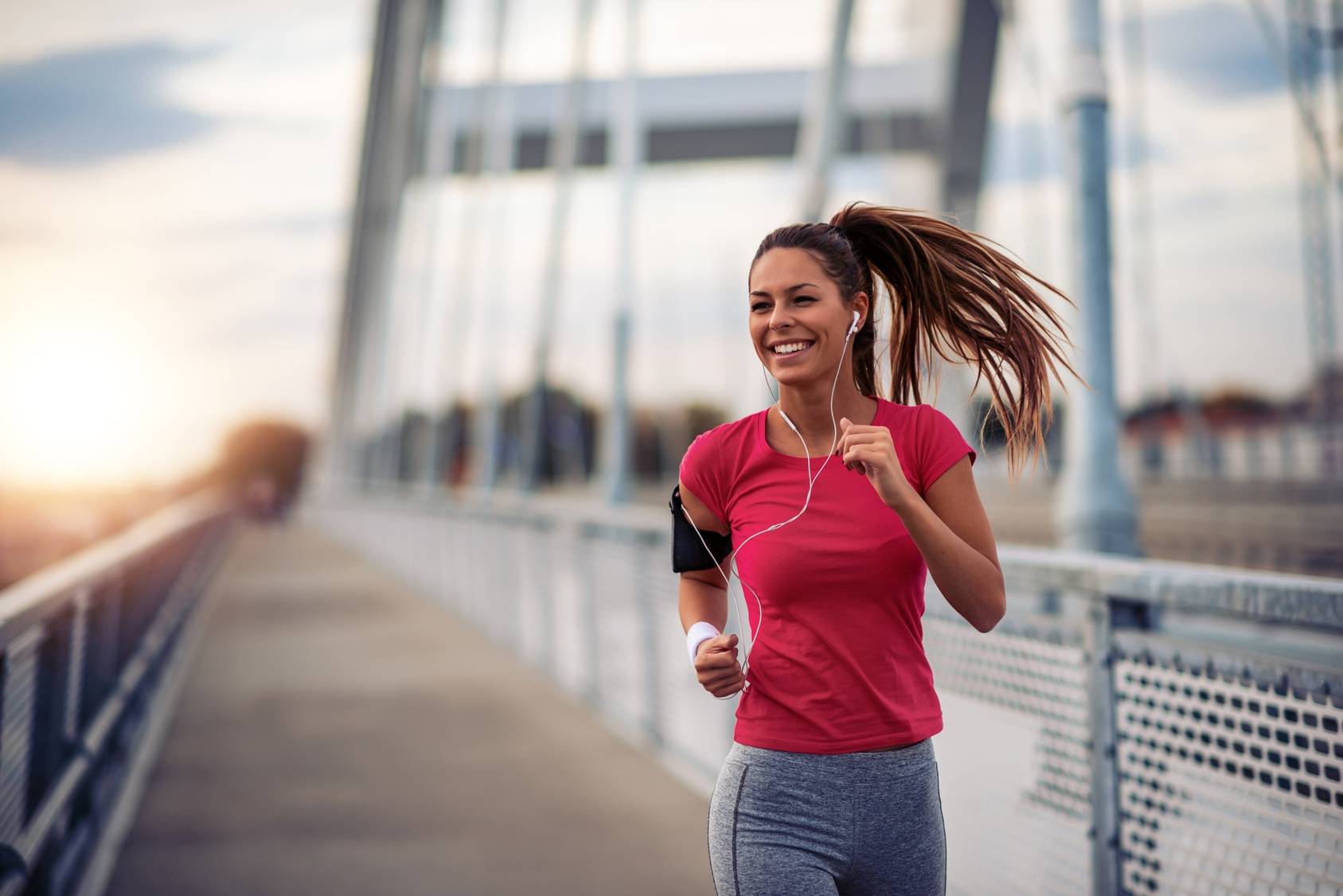 Poranny jogging - co jeść przed treningiem, a co po treningu? Kobieta biega po mieście ze słuchawkami w uszach.