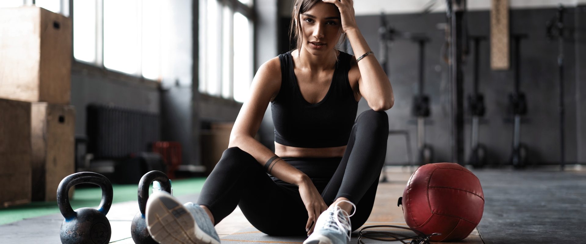 Trening na siłowni dla kobiet. Młoda atrakcyjna kobieta w stroju sportowym odpoczywa na macie po treningu na siłowni.