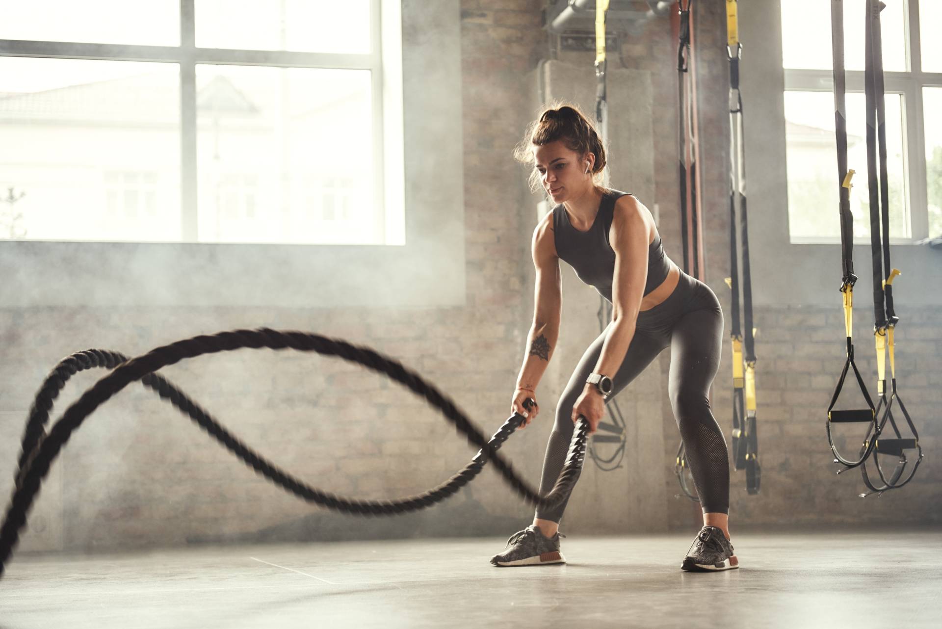 Trening na siłowni. Młoda kobieta ćwiczy crossfit z linami na siłowni.