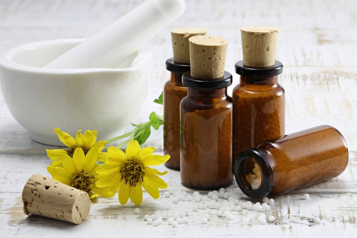 Arnica montana w formie leków homeopatycznych w brązowych fiolkach.
