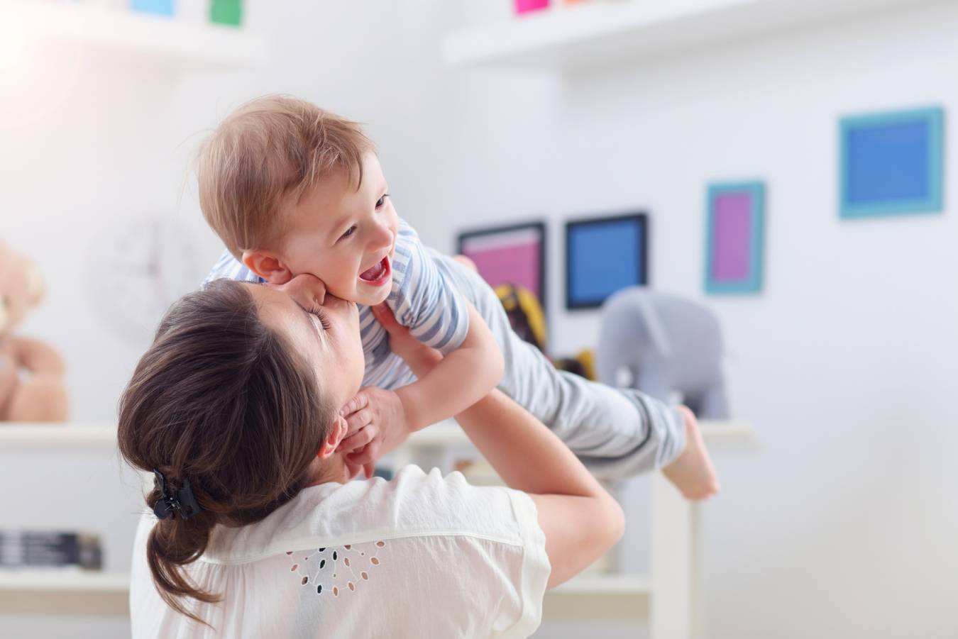 Jak leczyć zapalenie krtani u dzieci? Mama całuje synka i podnosi go do góry.