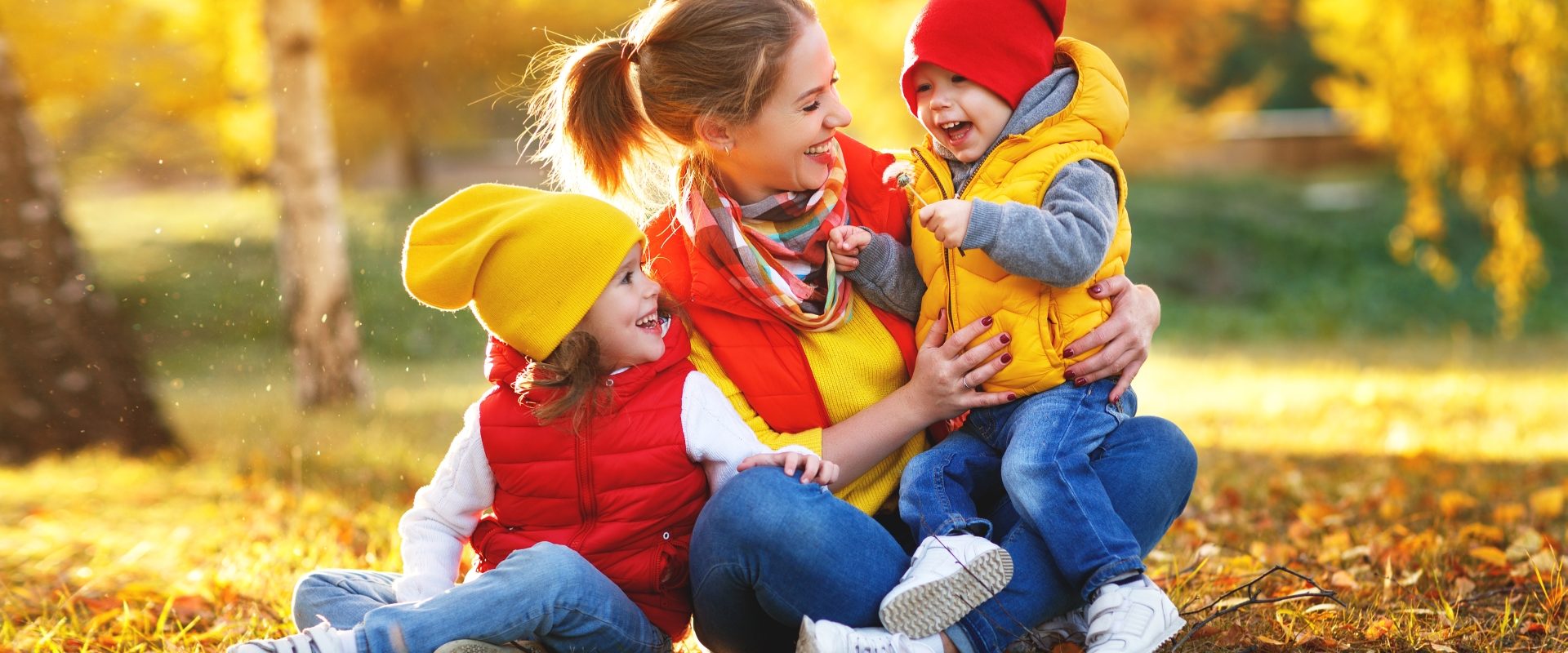 Jak zadbać o siebie jesienią wg medycyny chińskiej? Mama z dziećmi bawi się w jesiennych liściach.
