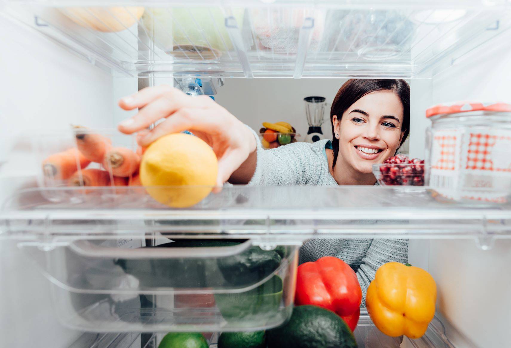 Co to jest foodsharing i jak działa jadłodzielnia w Polsce? W jaki sposób możemy się dzielić jedzeniem, by go nie marnować? Kobieta zagląda do lodówki.