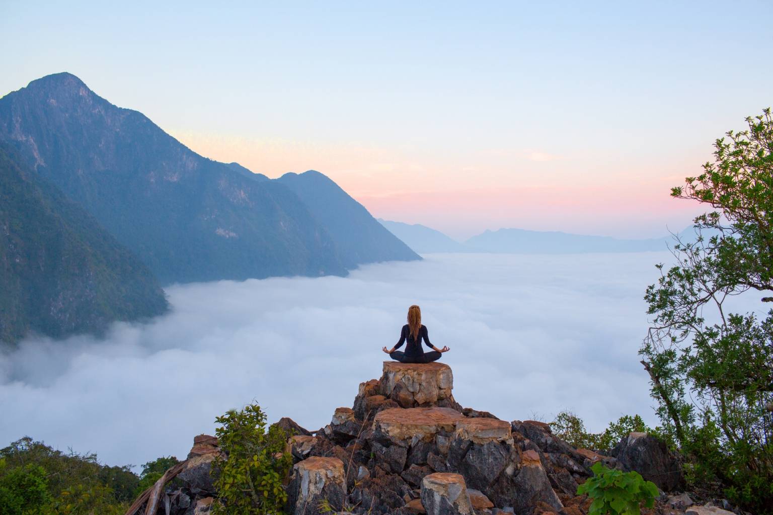 Mindfulness - trening uważności. Kobieta medytuje na skale w górach.