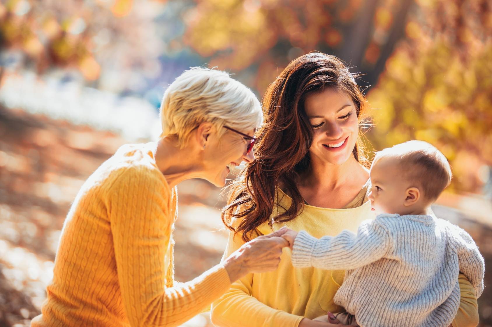 Relacje matka i córka - gdy córka zostaje matką. Mama i babcia z niemowlęciem na spacerze w parku jesienią.