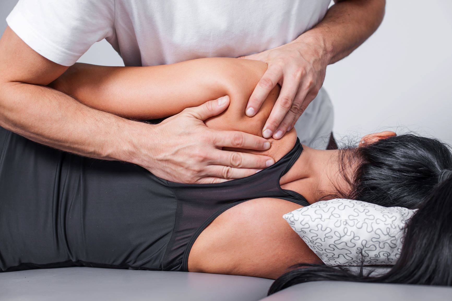 Masaż rolfing - terapia manualna. Fizjoterapeuta wykonuje masaż powięzi kobiety.