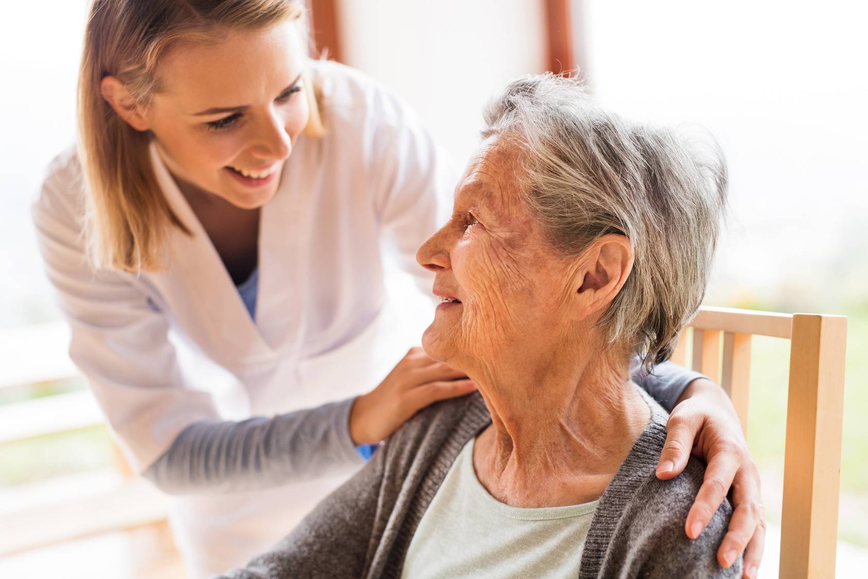 Suplementy wapnia nie zapobiegają osteoporozie. Pielęgniarka z troską dogląda seniorkę.