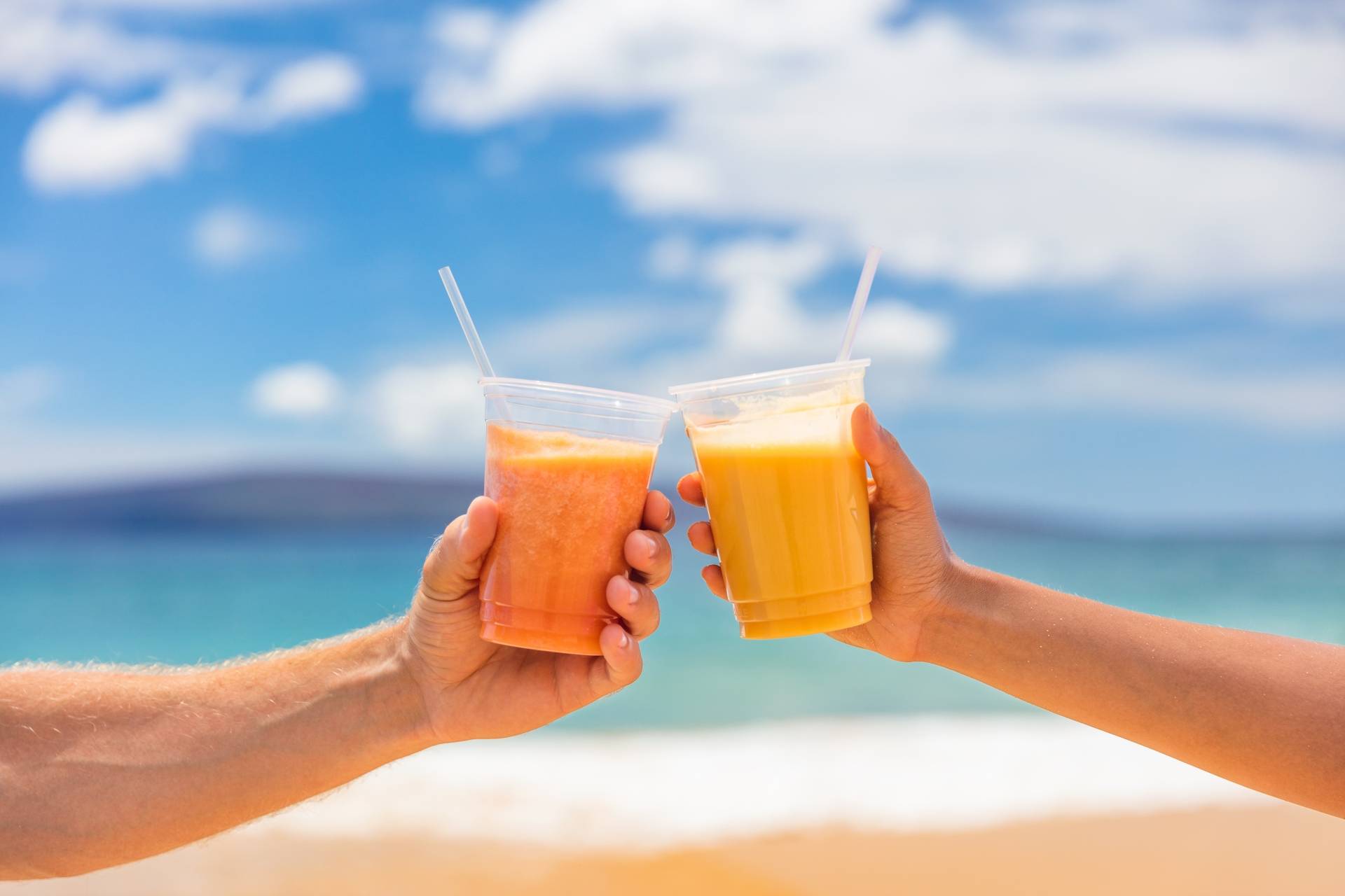 Beta-karoten - para wznosi toast sokiem marchewkowym, wypoczywając na plaży
