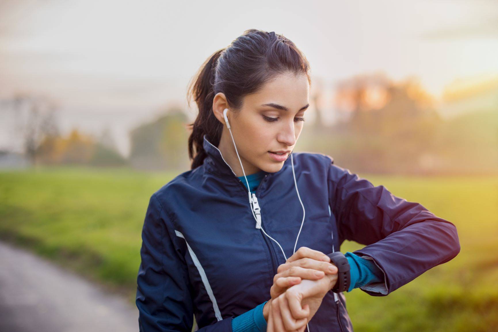 Trening z pulsometrem - czy warto? Młoda wysportowana kobieta uprawia jogging i sprawdza puls.