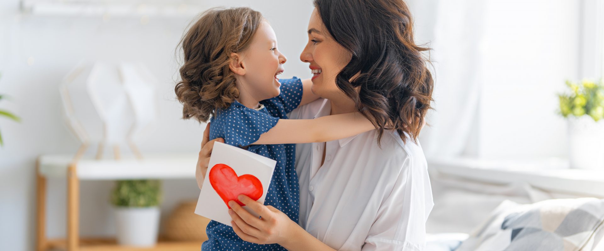 Przytul swoje wewnętrzne dziecko - wywiady z psycholożkami Joanną Caffo i Joanną Kot. Mama przytula córkę, która podarowała jej laurkę z sercem - metafora wewnętrznego dziecka.