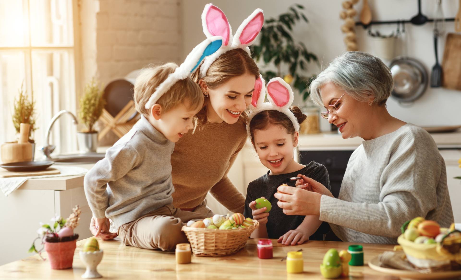 Malowanie jajek - jak zrobić ekologiczne pisanki wielkanocne? Babcia, mama i dzieci malują wspólnie jajka wielkanocne.