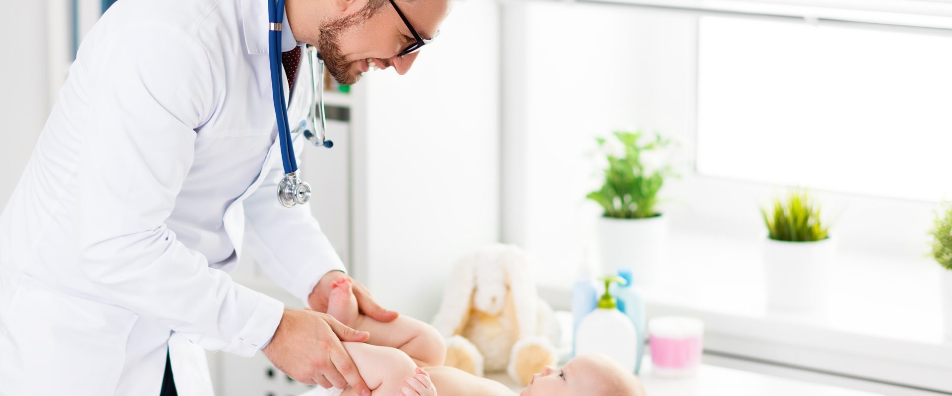 Zapalenie spojówek u dzieci - jak je leczyć? Doktor bada niemowlę na kozetce.